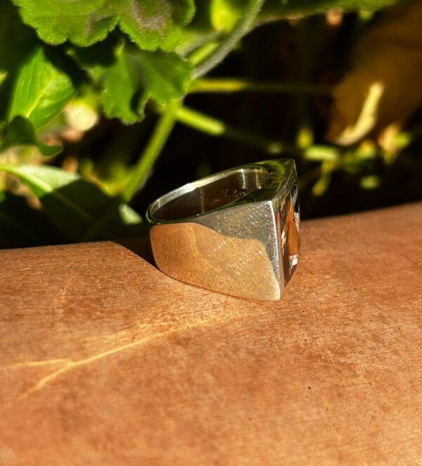 A silver ring with a square-shaped brown stone.