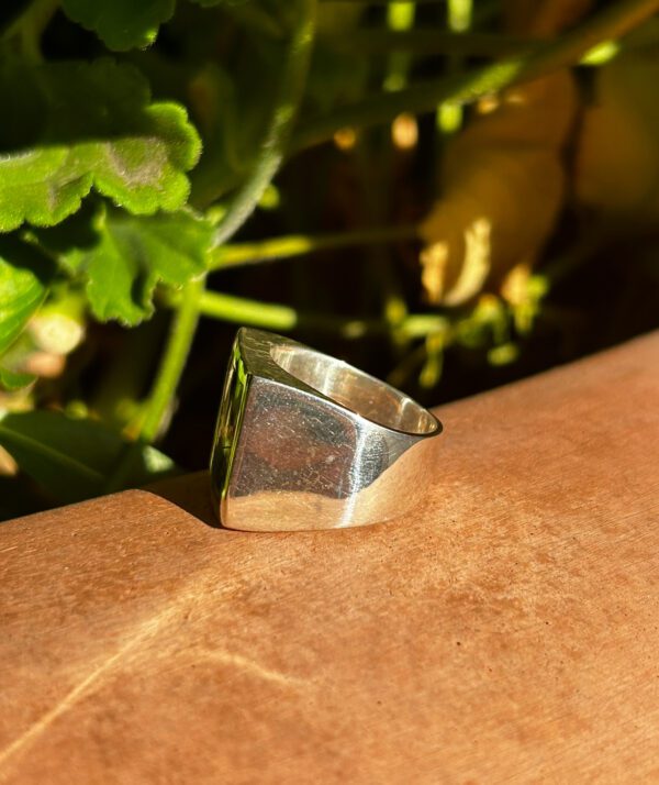 A silver square ring on a wooden surface.