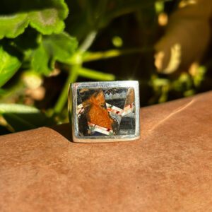 A square silver ring with colorful inlays.