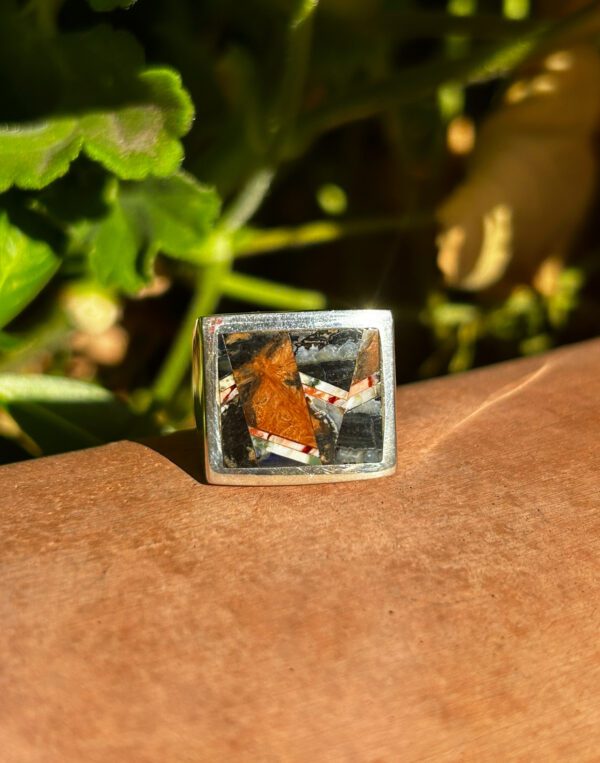 A square silver ring with colorful inlays.