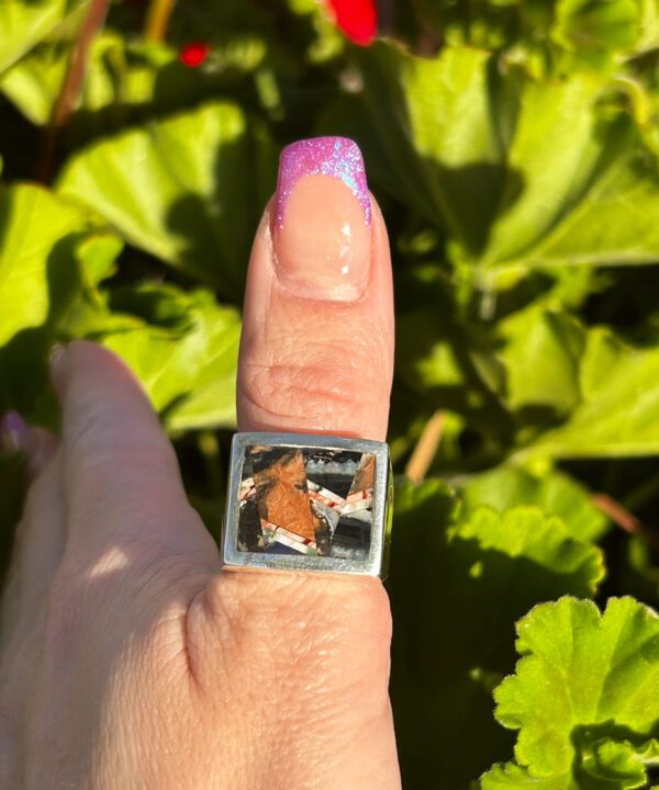 A square silver ring with a colorful stone inlay.