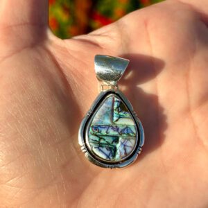 A silver pendant with a colorful stone inlay.