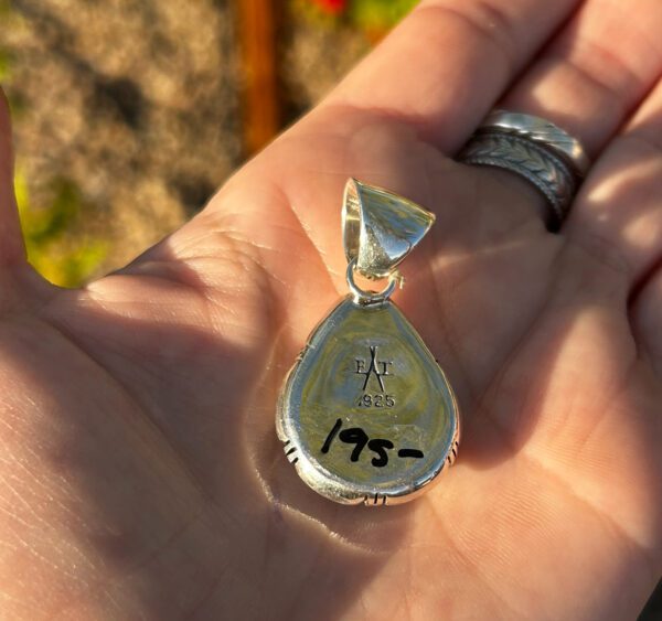 A silver pendant with a stone in the center.