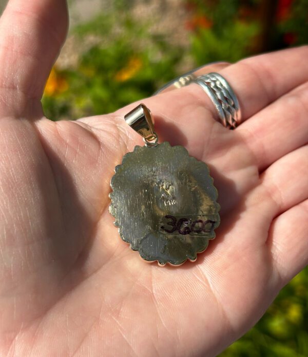 A hand holding a gold-colored pendant.