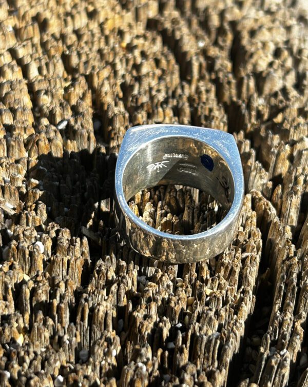 A silver square ring with a blue stone.