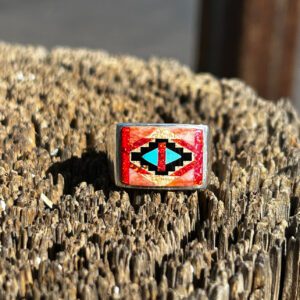 A silver ring with red, blue, and orange stones.