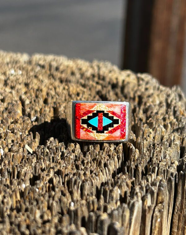 A silver ring with red, blue, and orange stones.