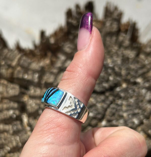 A person wearing a silver ring with a blue stone.