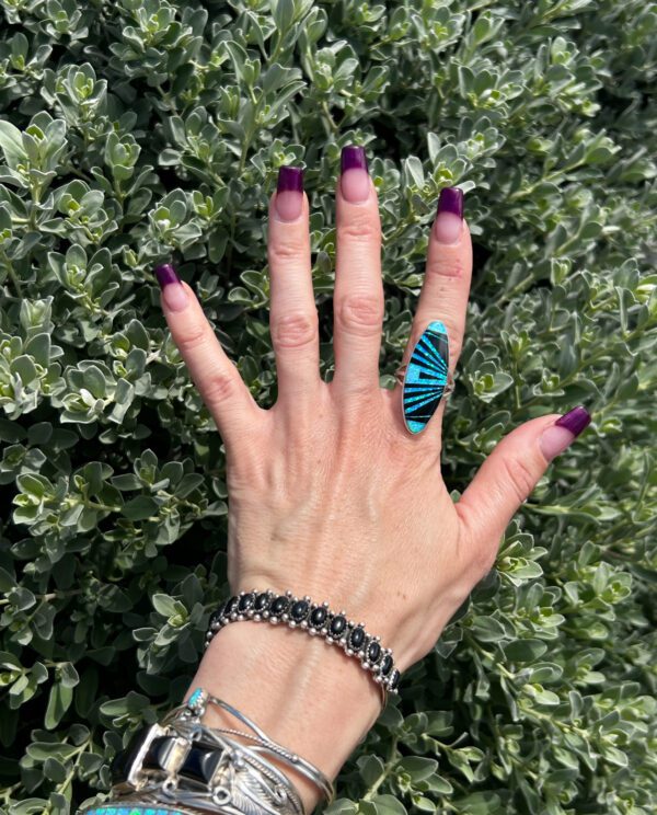 A hand wearing a silver and turquoise ring.