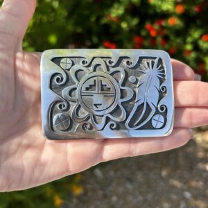 A silver belt buckle with a Native American design.