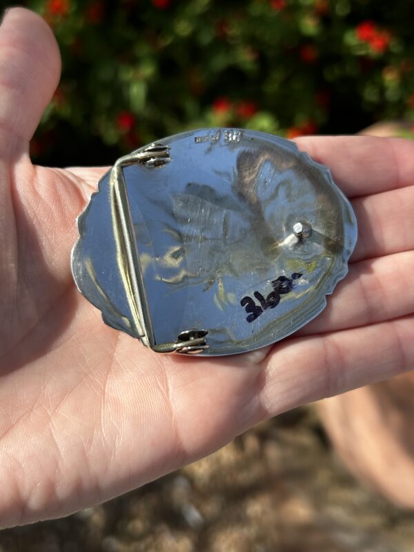 Hand holding a silver belt buckle.