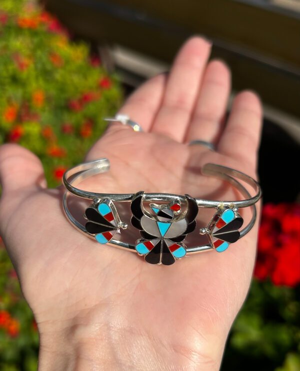 A silver bracelet with colorful inlaid stones.