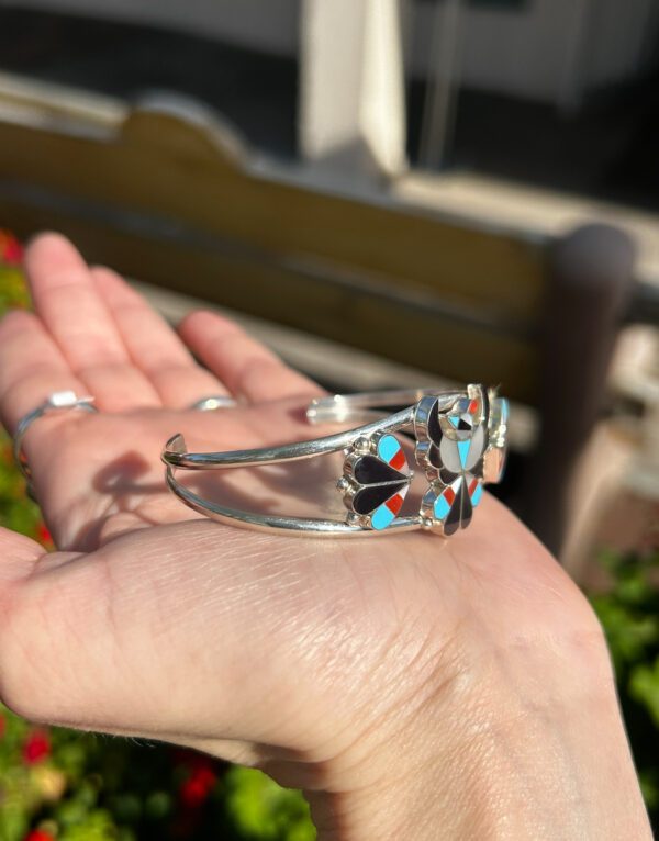 A silver bracelet with colorful stone inlay.