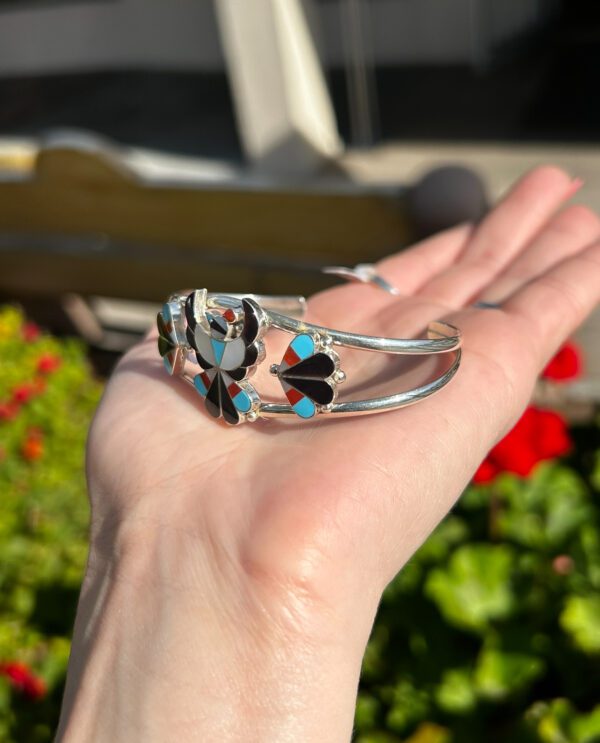 A silver bracelet with colorful stone inlay.