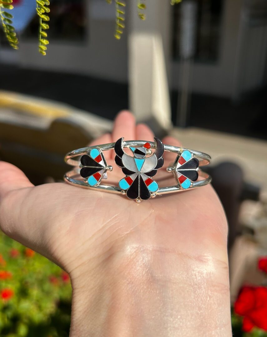 A silver bracelet with colorful inlaid stones.