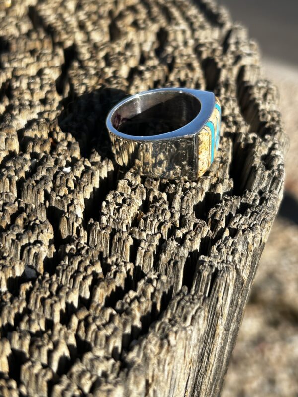 A silver ring with turquoise and wood inlay.