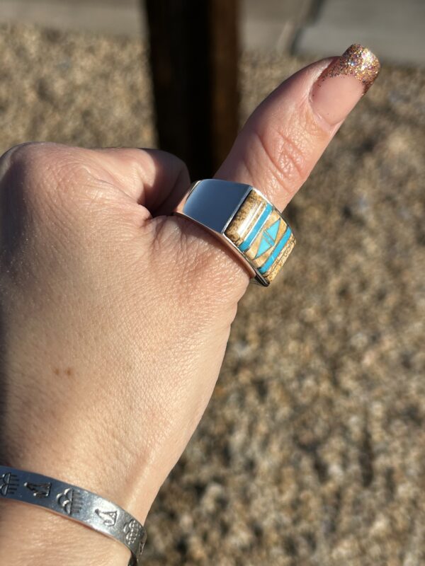 A person wearing a silver ring with turquoise inlay.