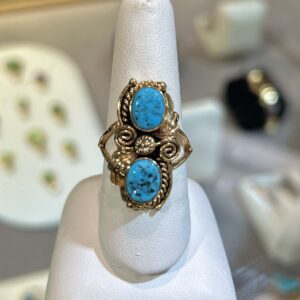 Gold ring with two turquoise stones.