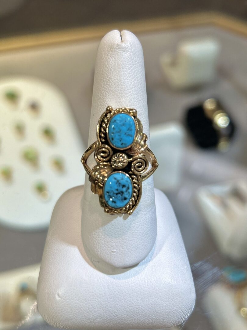 Gold ring with two turquoise stones.