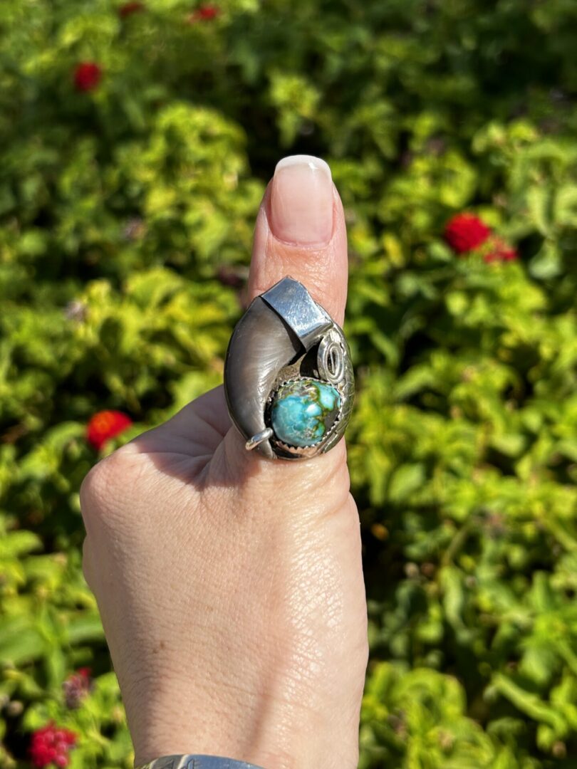 Turquoise and silver claw ring on finger.