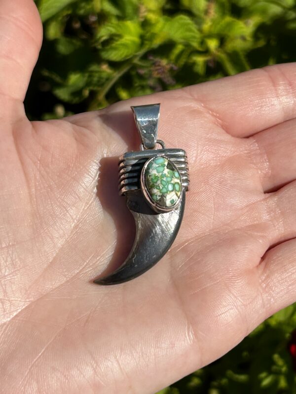 Silver claw pendant with turquoise stone.