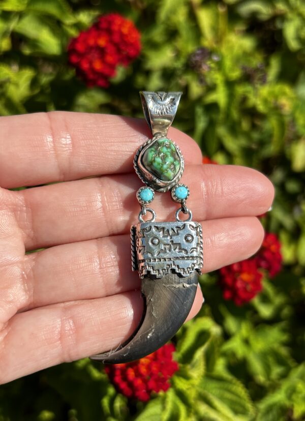 Silver bear claw pendant with turquoise stones.