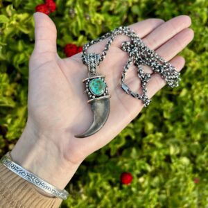 Silver claw pendant necklace with turquoise stone.