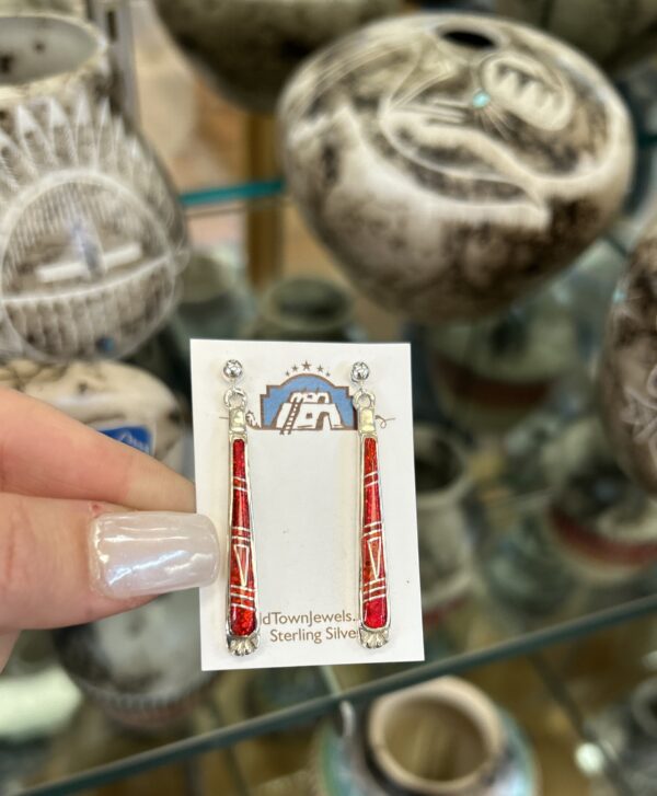 Red and silver dangle earrings on display.