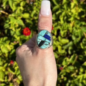 Turquoise and silver inlay ring on finger.