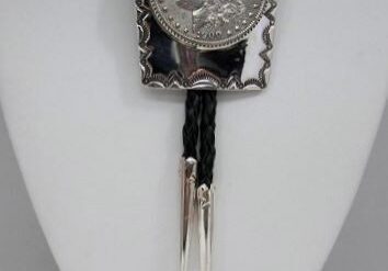 A silver coin is on the end of a black leather cord.